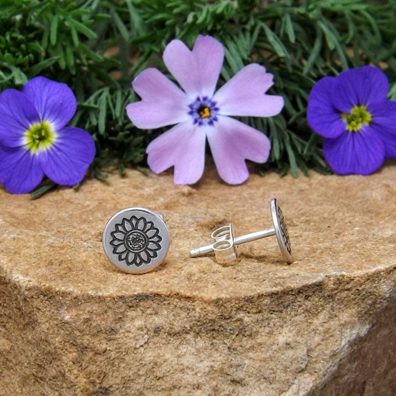 Side view of sterling silver stud earrings hand-stamped with sunflower design.