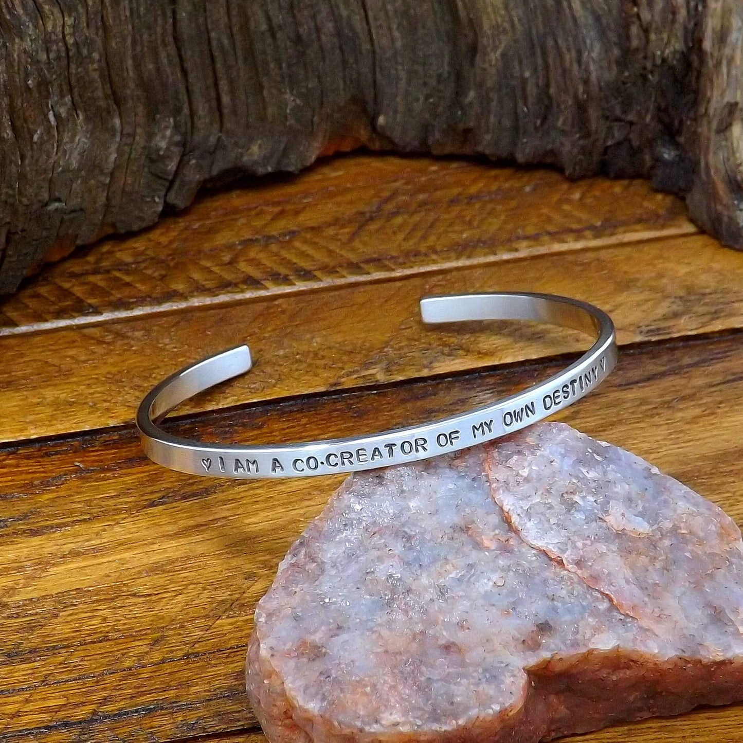 Left side view of a sterling silver affirmation cuff bracelet hand-stamped with "I AM A CO-CREATOR OF MY OWN DESTINY".