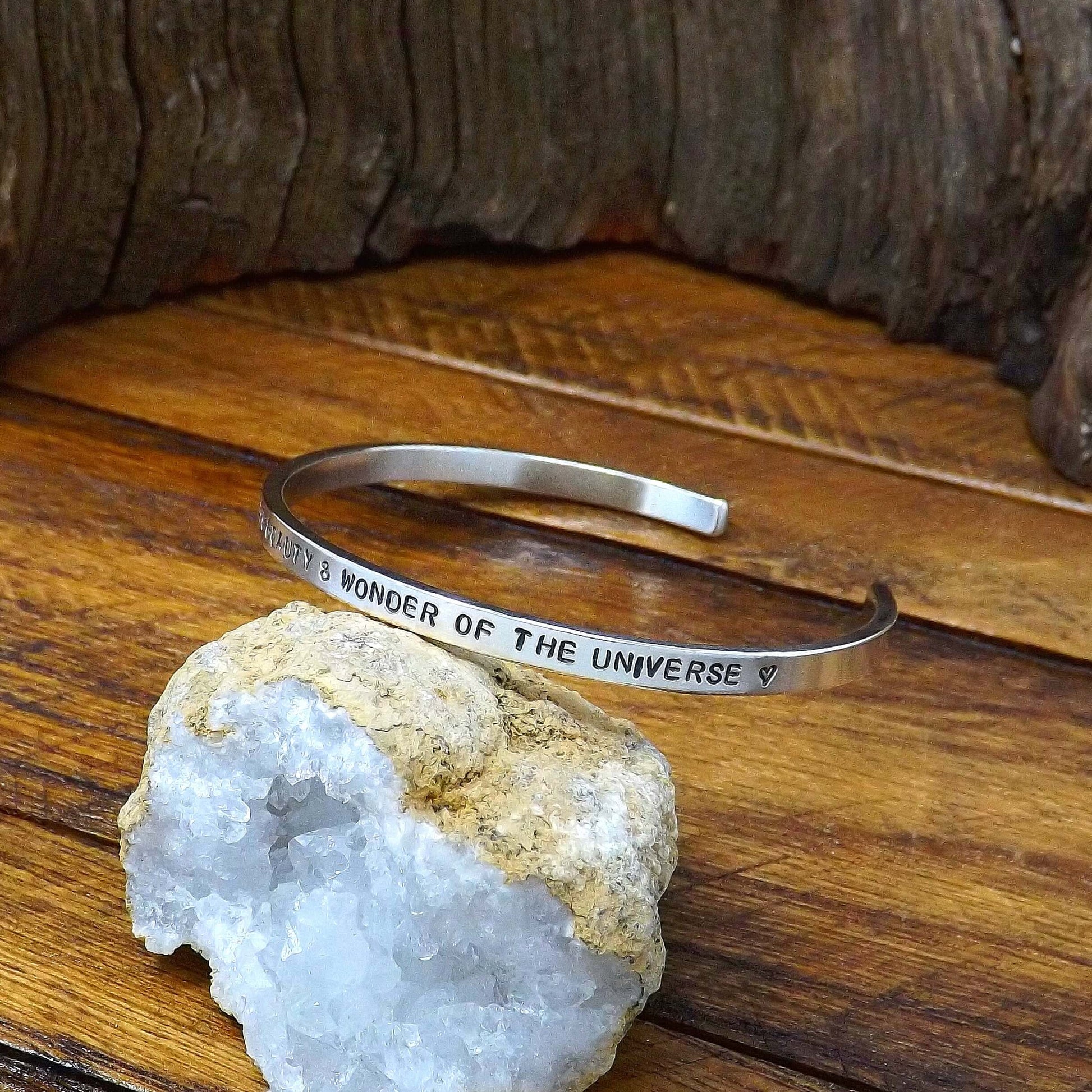 Right side view of a sterling silver affirmation cuff bracelet hand-stamped with "I AM A REFLECTION OF THE BEAUTY & WONDER OF THE UNIVERSE".