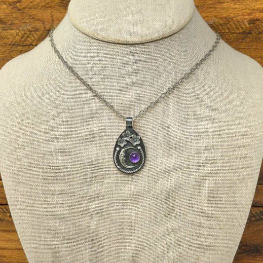 Sterling silver cherry blossom and crescent moon necklace with a rose cut faceted amethyst gemstone displayed on a necklace bust.