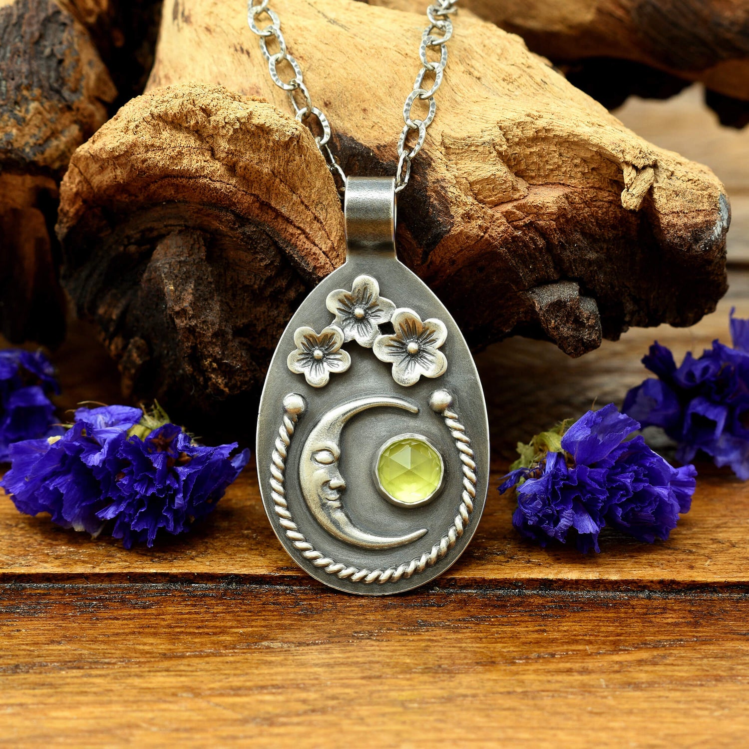 Front view of a sterling silver cherry blossom and crescent moon necklace with a rose cut faceted peridot gemstone.