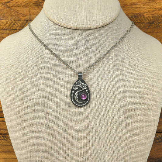 Sterling silver cherry blossom and crescent moon necklace with a rose cut faceted rhodolite garnet shown on a display bust.