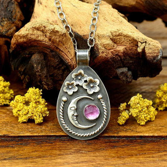 Sterling silver cherry blossom and crescent moon necklace with a rose cut faceted rhodolite garnet, front view.