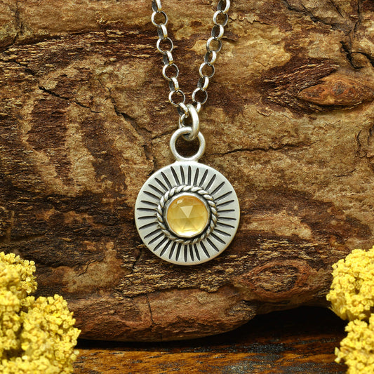 Front view of a sterling silver sunburst necklace with a rose cut faceted citrine gemstone.