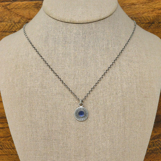Bust view of a sterling silver sunburst necklace with a rose cut faceted iolite gemstone.
