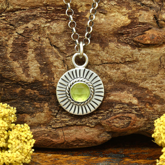 Front view of a sterling silver sunburst necklace with a rose cut faceted peridot gemstone.