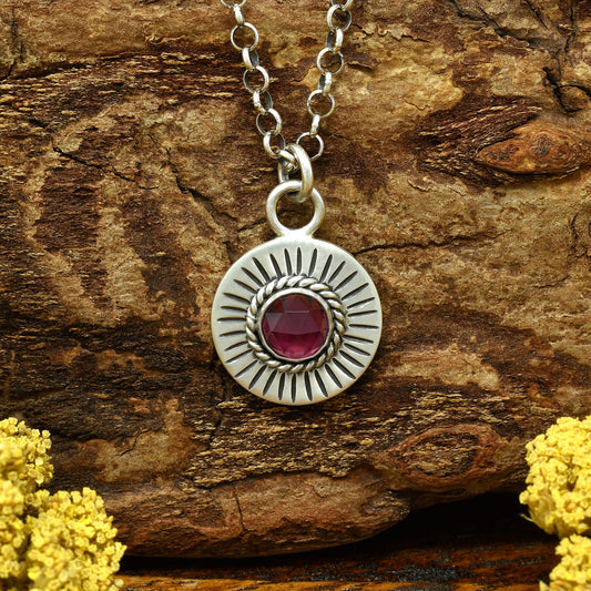Front view of a sterling silver sunburst necklace with a rose cut faceted rhodolite garnet gemstone.