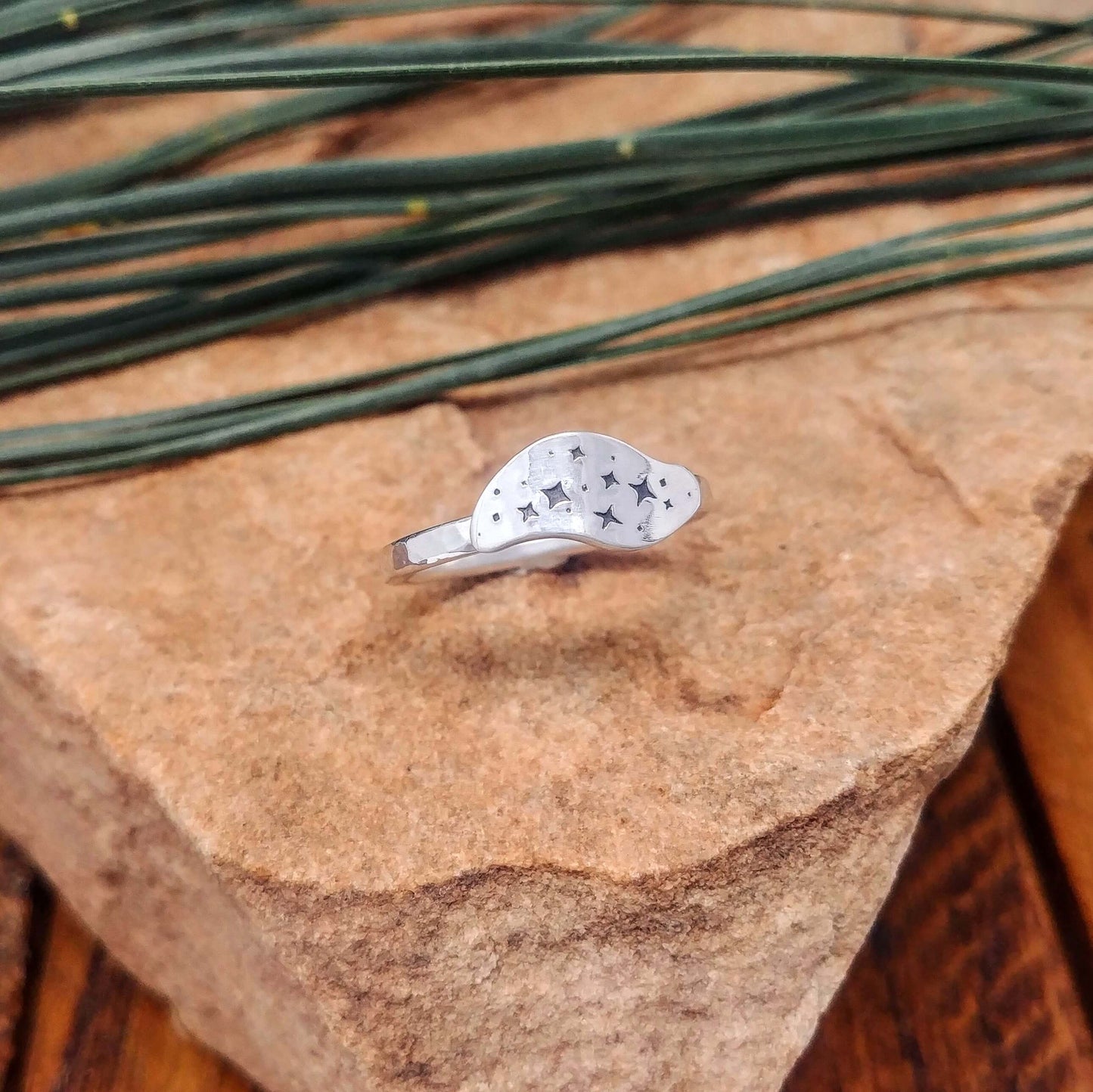 Left angle view of a sterling silver ring hand-stamped with a star cluster design.