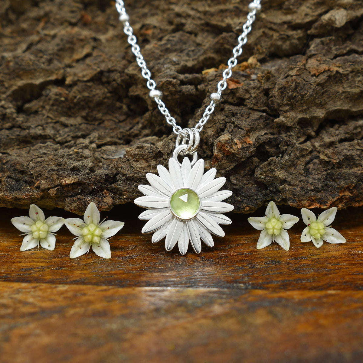 A sterling silver peridot necklace with a faceted amethyst at the flower center.