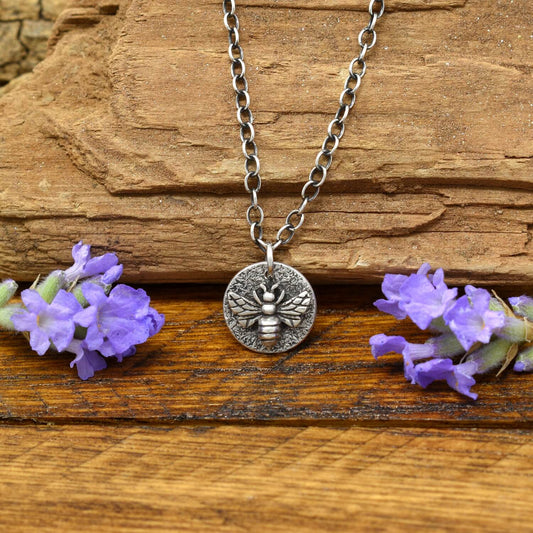 Hand-fabricated sterling silver heart necklace with a 3-dimensional bee on a hand-stamped textured disc.