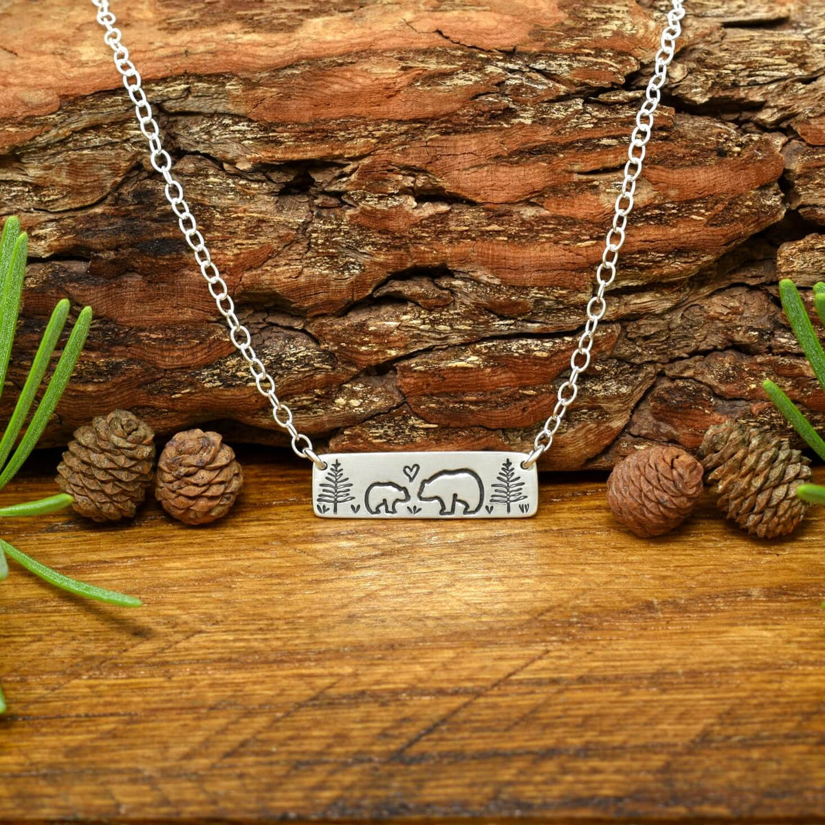 Hand-stamped sterling silver mama bear and baby bear bar necklace with trees and a small heart.