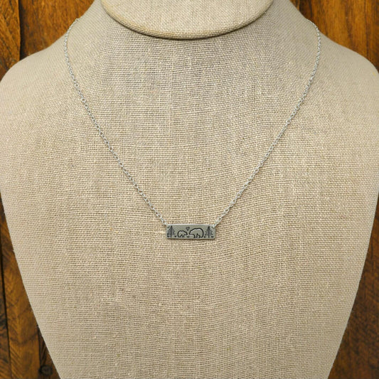 Sterling silver mama bear and baby bear bar necklace with hand-stamped woodland scene, display on a necklace bust.