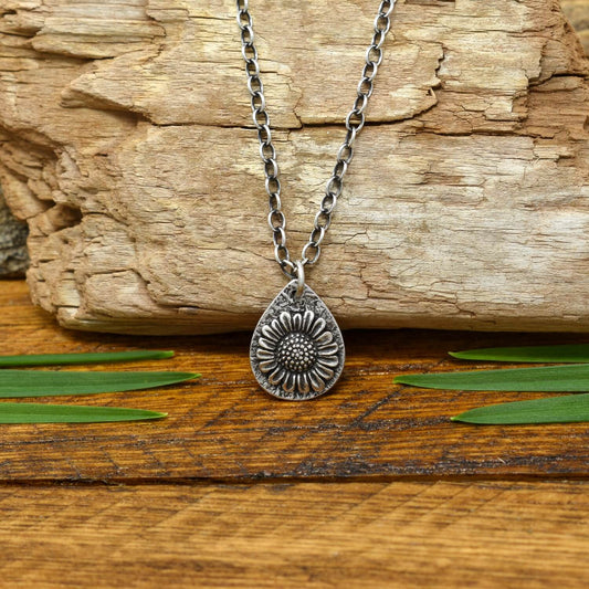 Hand-fabricated sterling silver necklace with a 3-dimensional sunflower on a hand-stamped textured teardrop shaped silver disc.
